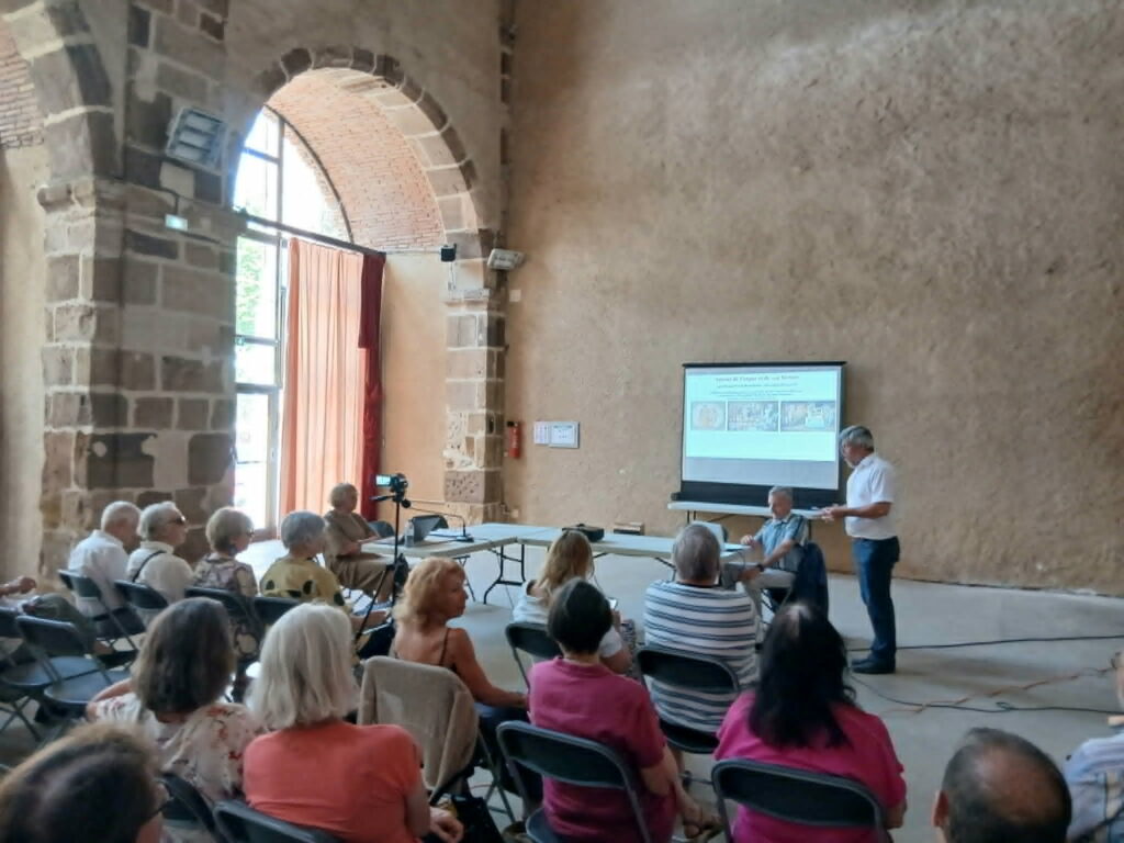 public écoutant une conférence dans une salle en pierre