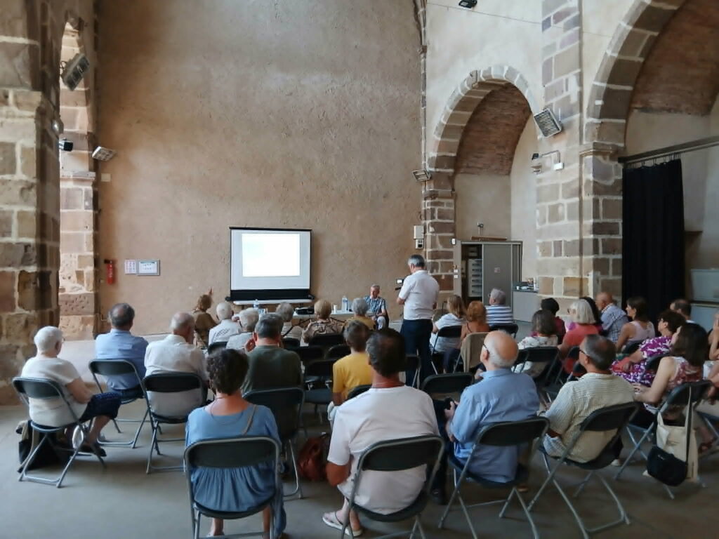 public écoutant une conférence dans une salle en pierre